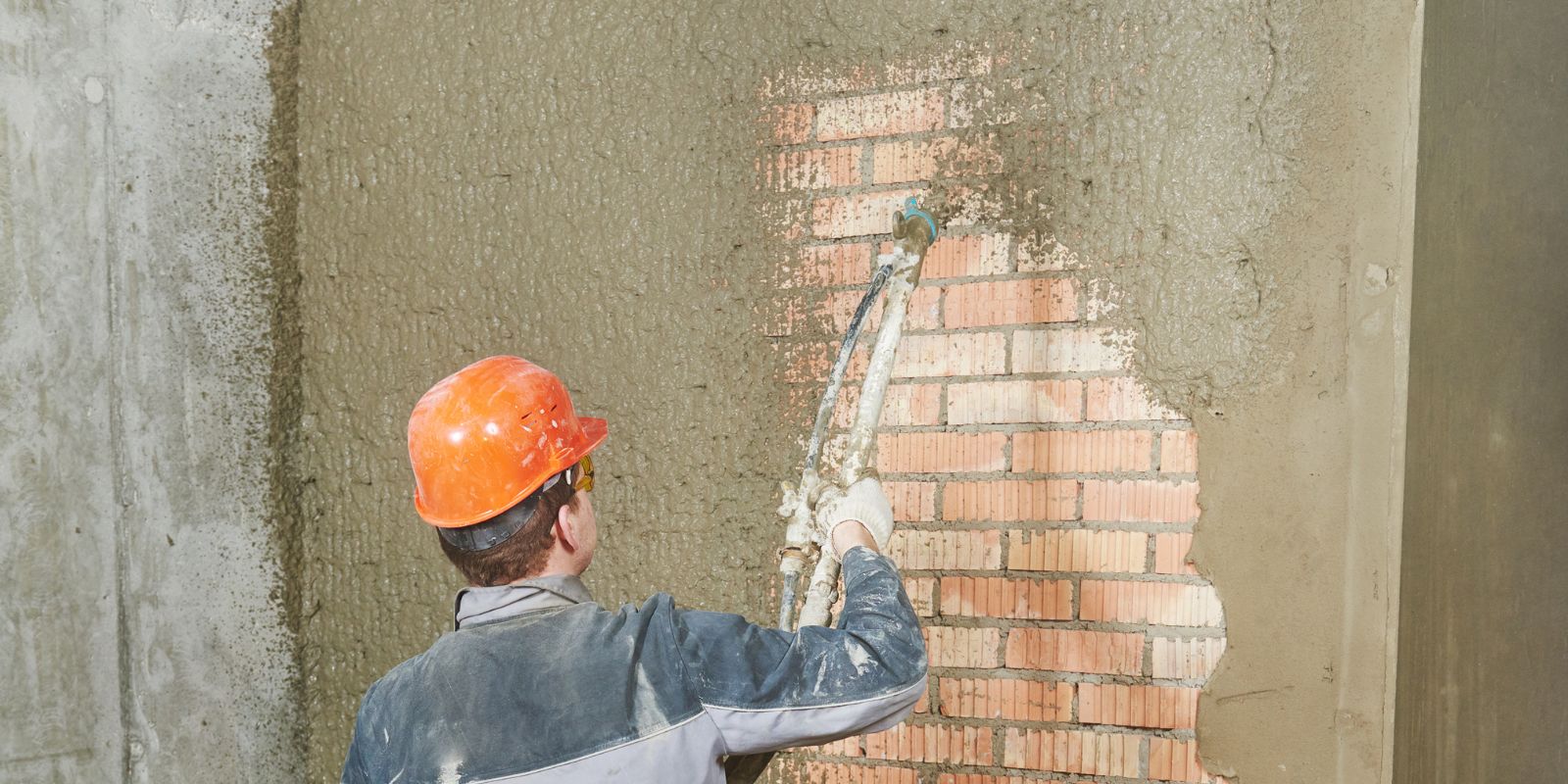 Fachowiec nakładający tynki maszynowe w Nowym Targu przy użyciu agregatu tynkarskiego we wnętrzu budynku